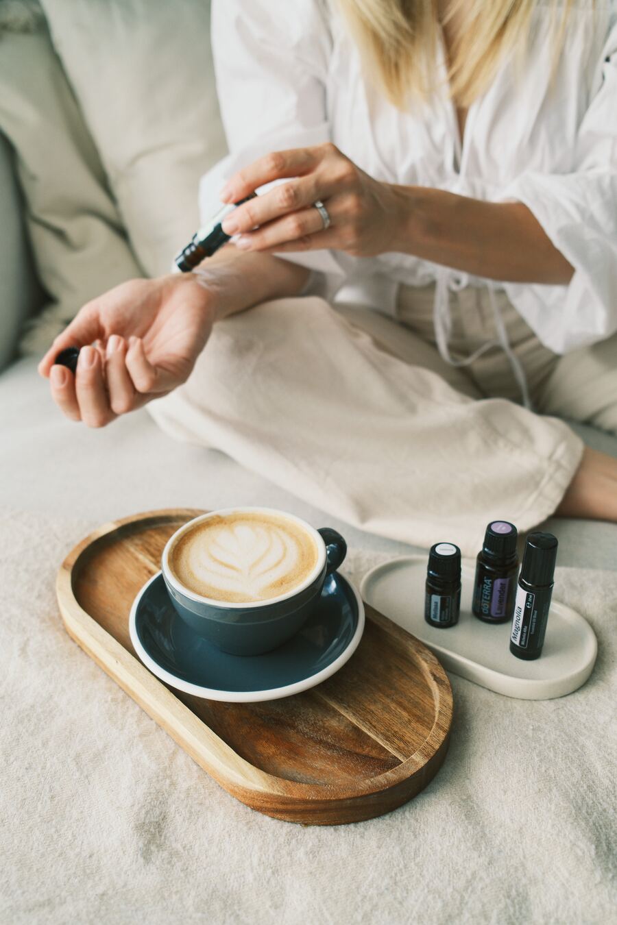 Applying a roller oil to the wrist beside a morning coffee