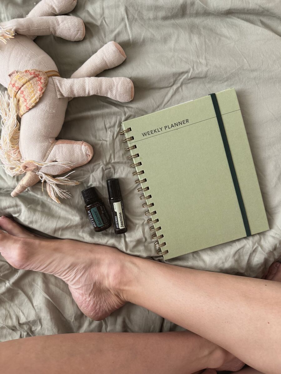 A weekly planner with Balance and Jasmine oils on the bed